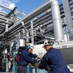 Men standing in front of pipes